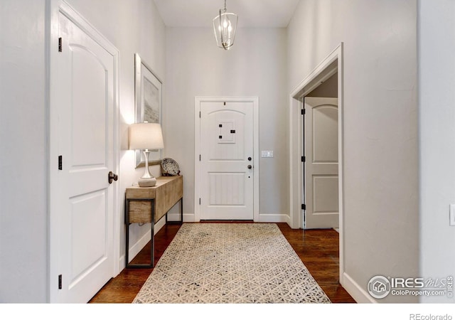 entryway with dark wood-style flooring, baseboards, and an inviting chandelier