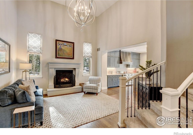 living room with light wood-type flooring, a healthy amount of sunlight, a lit fireplace, and stairway