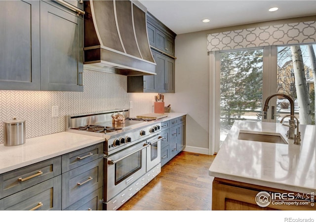 kitchen featuring wall chimney exhaust hood, tasteful backsplash, a sink, and double oven range