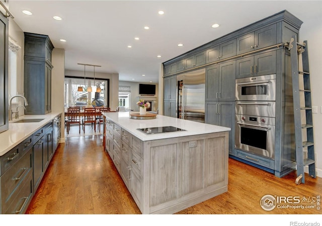 kitchen with light wood-style floors, stainless steel appliances, a sink, and a center island