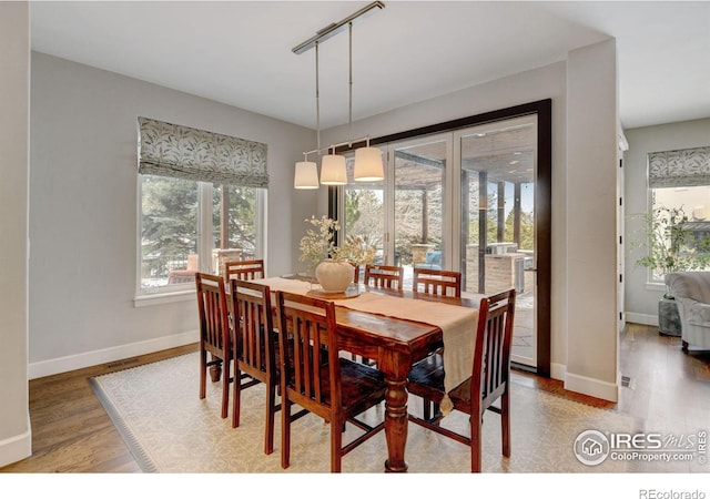 dining room featuring visible vents, track lighting, baseboards, and wood finished floors