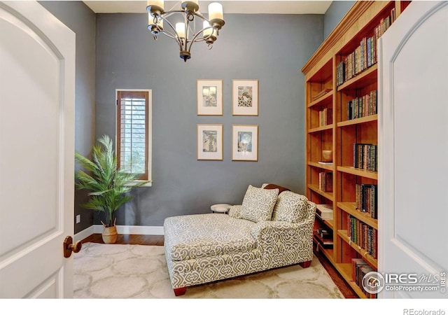 living area featuring a chandelier, wood finished floors, and baseboards