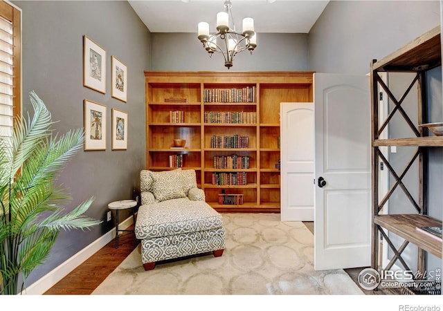 sitting room with a notable chandelier, baseboards, and wood finished floors