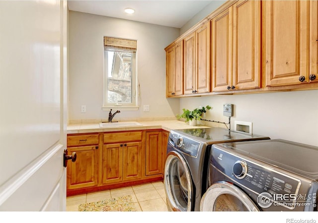 laundry room with washing machine and dryer, cabinet space, a sink, and light tile patterned floors