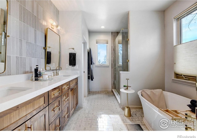 full bath with a freestanding tub, recessed lighting, a sink, double vanity, and a stall shower