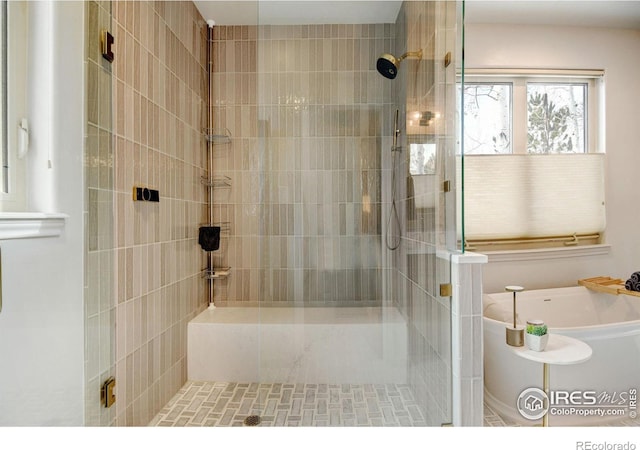 full bathroom with a tub to relax in and a shower stall