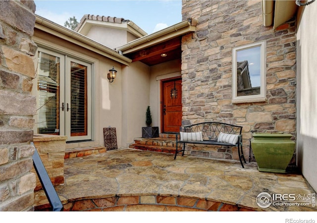 doorway to property with stone siding, french doors, and a patio