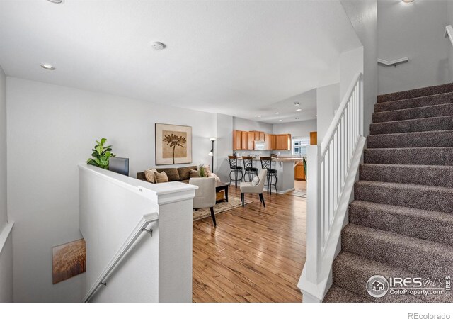 living area with light wood-style floors, recessed lighting, and stairs