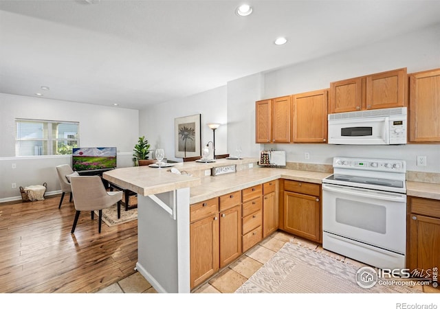 kitchen with a peninsula, white appliances, light countertops, and recessed lighting