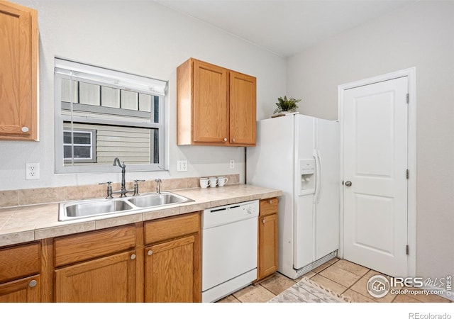 kitchen featuring brown cabinetry, white appliances, light countertops, and a sink