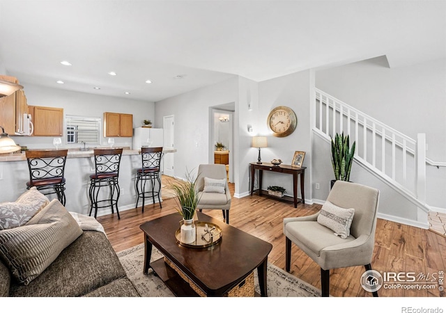 living room with light wood-style floors, recessed lighting, stairway, and baseboards