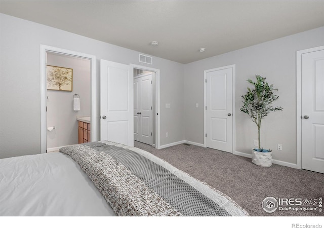 carpeted bedroom featuring ensuite bathroom, visible vents, and baseboards