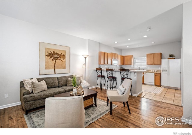 living room featuring light wood-style floors, recessed lighting, and baseboards