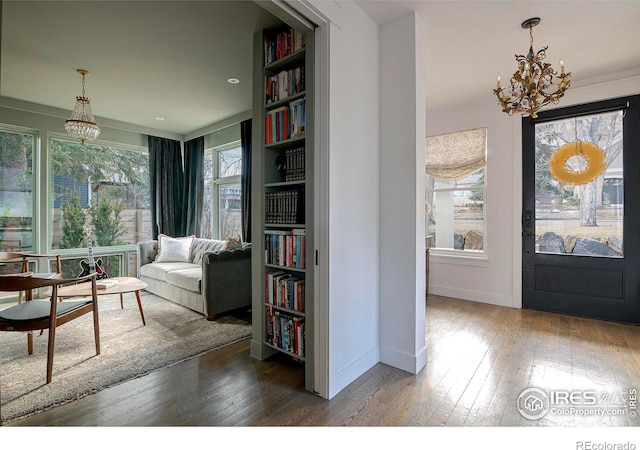 sitting room with a chandelier, a wealth of natural light, wood-type flooring, and baseboards