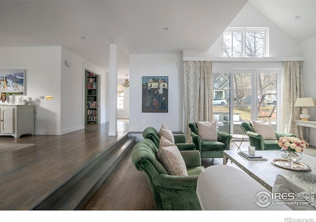 living area with high vaulted ceiling, wood finished floors, and baseboards