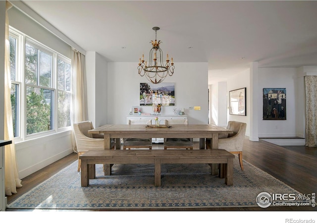 dining space with baseboards, wood finished floors, and an inviting chandelier