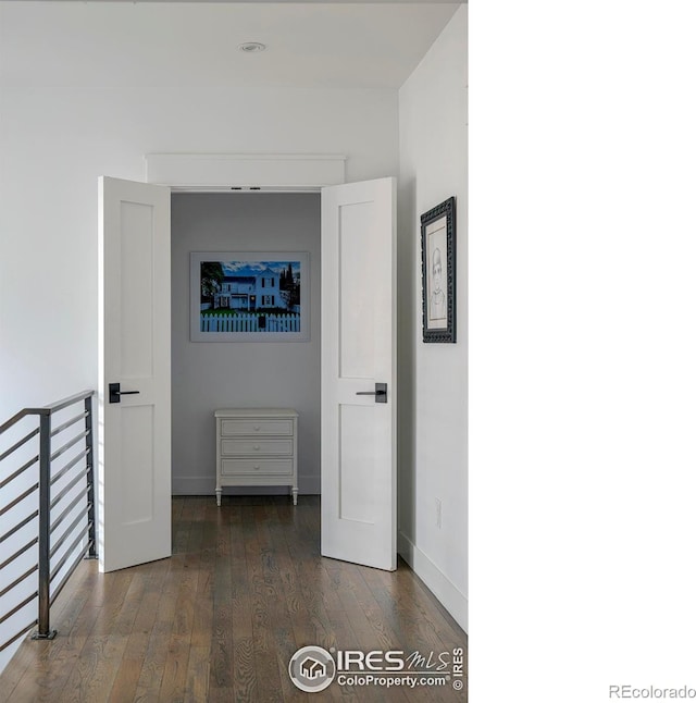 corridor featuring hardwood / wood-style flooring, baseboards, and an upstairs landing