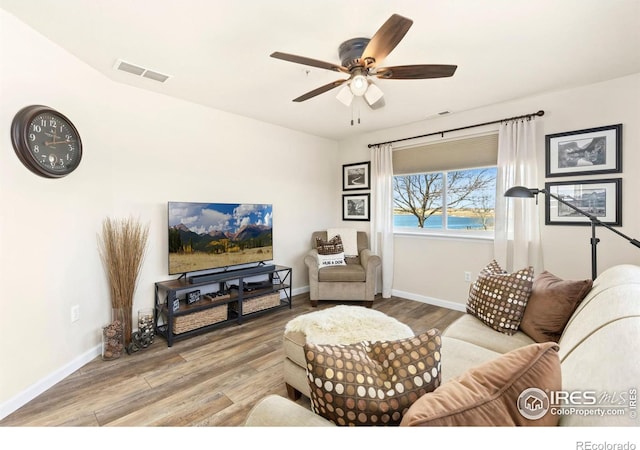 living room featuring baseboards, visible vents, and wood finished floors