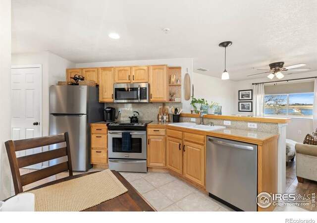 kitchen with a peninsula, a sink, stainless steel appliances, backsplash, and light tile patterned flooring