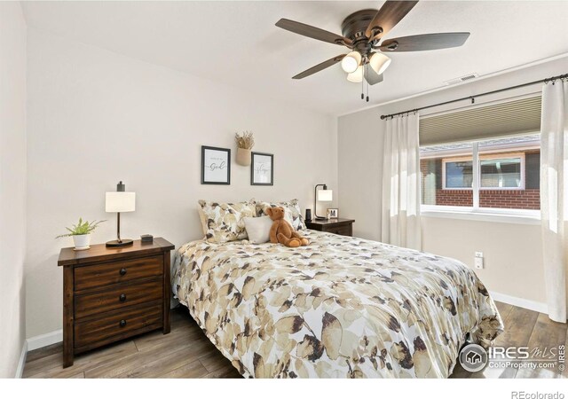 bedroom with a ceiling fan, baseboards, visible vents, and wood finished floors