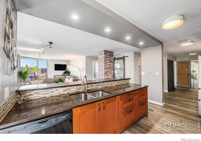 kitchen with black dishwasher, tasteful backsplash, a barn door, a sink, and wood finished floors