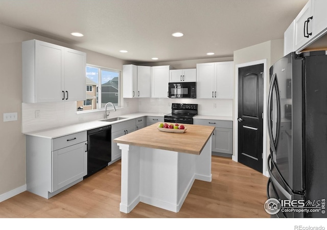 kitchen featuring a sink, black appliances, butcher block counters, and light wood finished floors