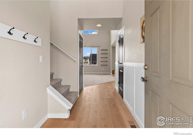 foyer entrance with stairs, light wood-style flooring, baseboards, and visible vents