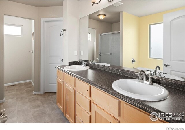 bathroom featuring double vanity, a stall shower, and a sink