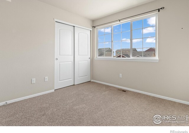 unfurnished bedroom featuring a closet, visible vents, baseboards, and carpet