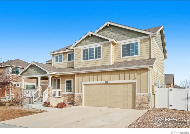 craftsman house with a porch, driveway, board and batten siding, and a gate