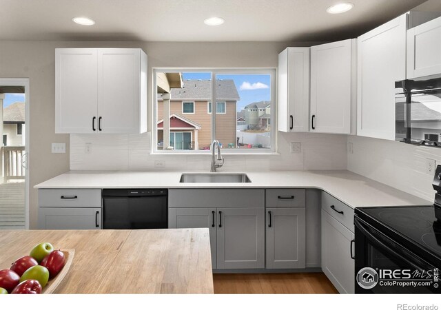 kitchen with gray cabinets, a sink, black appliances, light countertops, and backsplash