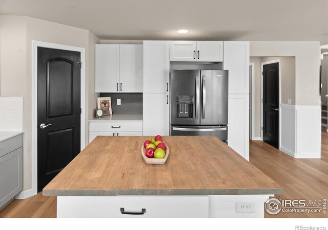 kitchen featuring white cabinetry, light wood-style flooring, stainless steel refrigerator with ice dispenser, and butcher block counters