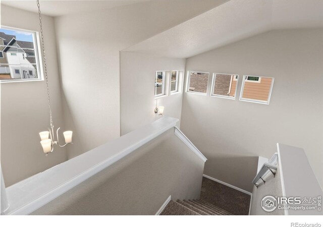 staircase with lofted ceiling and a notable chandelier