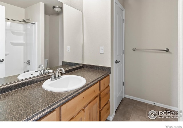 bathroom with baseboards, toilet, vanity, and tile patterned flooring