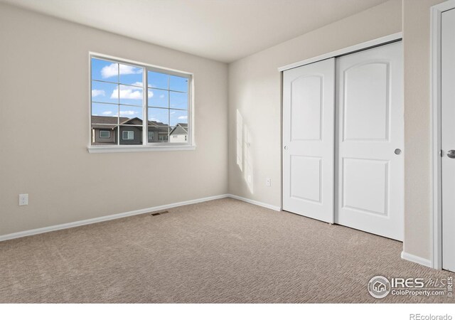 unfurnished bedroom featuring visible vents, carpet, a closet, and baseboards