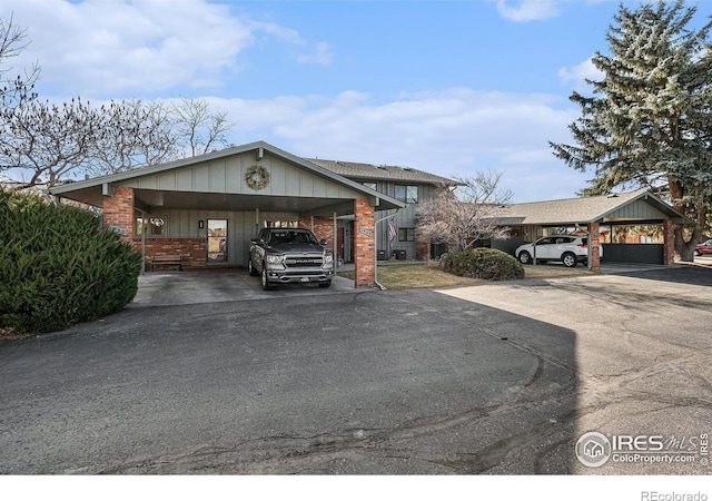 view of front facade featuring aphalt driveway, an attached carport, and brick siding