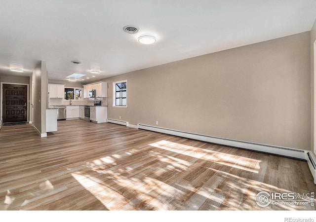 unfurnished living room featuring light wood-style floors, baseboards, visible vents, and baseboard heating