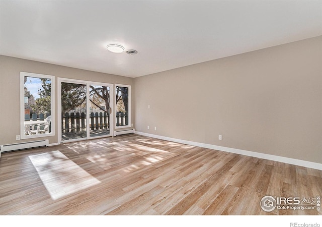 empty room with a baseboard radiator, baseboards, visible vents, and wood finished floors