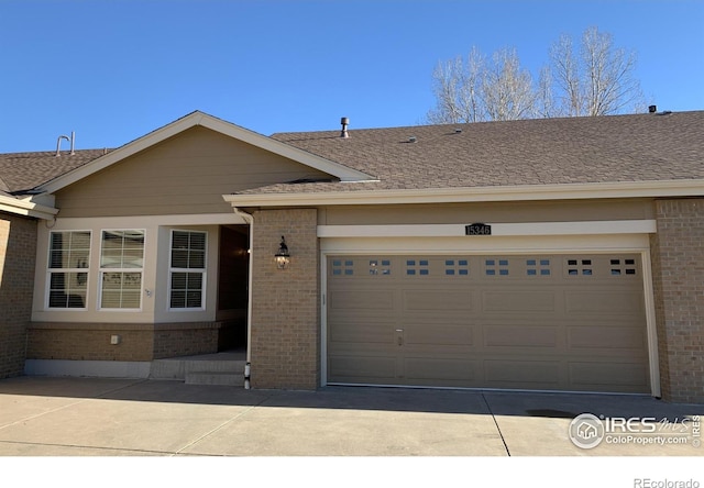 ranch-style home with a shingled roof, brick siding, driveway, and an attached garage