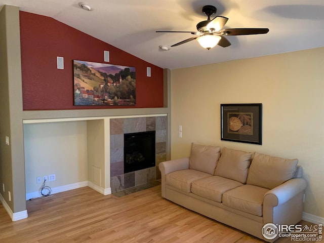 living room featuring a fireplace, lofted ceiling, a ceiling fan, light wood-type flooring, and baseboards