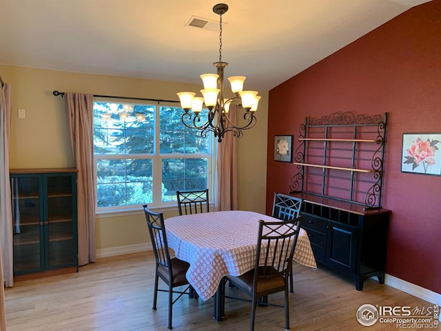 dining room featuring vaulted ceiling, light wood finished floors, an inviting chandelier, and baseboards