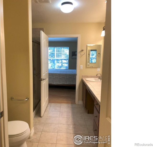 ensuite bathroom featuring toilet, visible vents, vanity, tile patterned floors, and ensuite bath