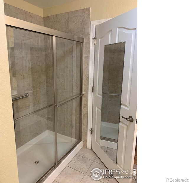 full bath with a shower stall and tile patterned flooring