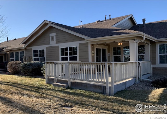 view of front of home with a front yard, roof with shingles, and a deck