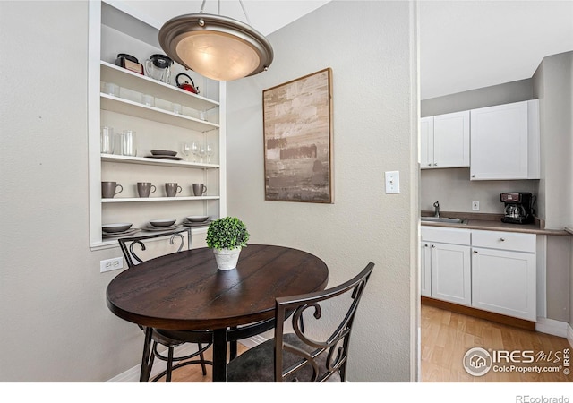 dining area with built in features, baseboards, and light wood finished floors