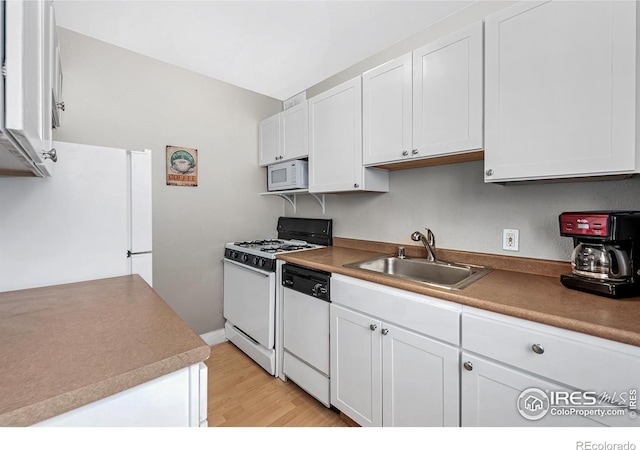 kitchen featuring light wood-type flooring, white appliances, white cabinets, and a sink