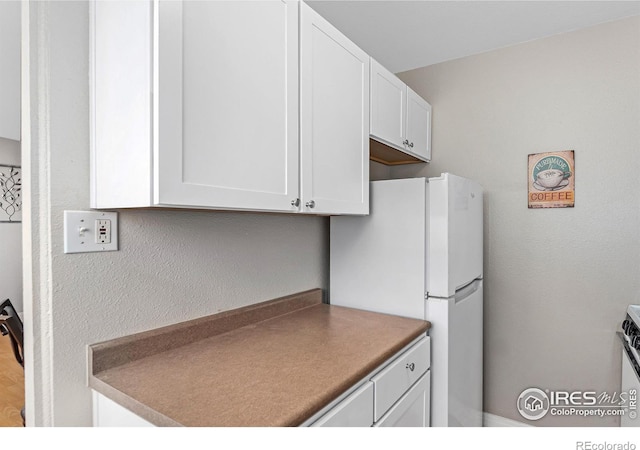 kitchen with freestanding refrigerator and white cabinets