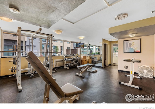 exercise room with a wealth of natural light, a textured ceiling, and baseboards