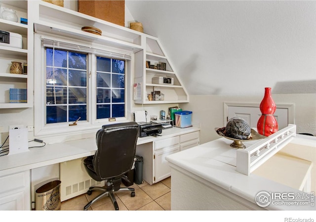 home office with light tile patterned floors, built in desk, and lofted ceiling