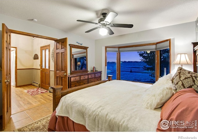 bedroom with a ceiling fan, a baseboard radiator, a textured ceiling, and tile patterned floors